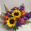 Colorful bouquet with sunflowers, roses, and purple blooms in a white vase