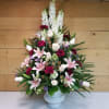 Tall floral arrangement in a white vase with pink lilies and white snapdragons