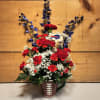 Red carnations and white filler flowers in a football mug with blue accents