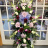 Standing floral spray with pink, white, and purple flowers on an easel