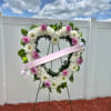 Heart-shaped floral wreath with pink roses and white flowers on an easel