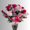 Bouquet of pink and red roses in a glass vase with a pink ribbon