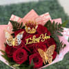 Bouquet of red roses with gold butterfly decorations and a "I Love You" topper