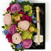 A pastel floral arrangement in a wood box paired with Chandon Brut