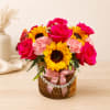 Pink roses and sunflowers in a wicker basket with a pink ribbon