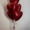 Cluster of red heart-shaped balloons tied with ribbon
