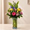 Mixed bouquet in a clear glass vase with pink, yellow, purple, and white flowers