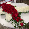 Red roses arranged over a white cross-shaped floral tribute