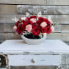 Red and pink roses arranged in a silver bowl vase