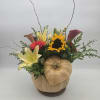 Fall floral arrangement in a pumpkin container with lilies, roses, and a sunflower