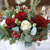 Red and white roses in a white vase with berries and greenery