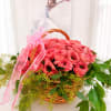 Pink roses in a wicker basket with a pink ribbon