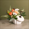 Orange roses and white anemones arranged in a white pumpkin vase