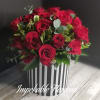 Round arrangement of red roses in a black and white striped cylinder box