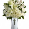 White lilies and daisies arranged in a silver vase with a cross