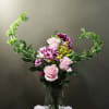 Pink roses and purple daisies in a clear glass vase