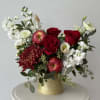 Red roses and white flowers arranged in a gold vase with apples