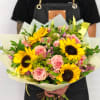 Handheld bouquet of pink roses and yellow sunflowers wrapped in pale paper
