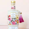 Floral-patterned bath bottle with a pink tassel and gold cap