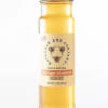 A jar of orange blossom honey with a black lid and labeled front