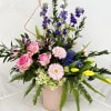 Mixed bouquet of pink roses, lilies, and purple flowers in a pink vase
