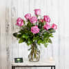 A dozen fragrant lavender roses arranged in a vase with textural greens