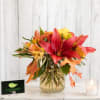 Autumn bouquet with red lilies and orange flowers in a gold glass vase