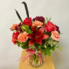 Bouquet of red roses, carnations, and a red lily in a glass vase
