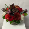 Red and burgundy floral arrangement in a clear glass vase