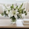 White lilies and roses arranged in a clear glass vase