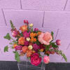 Mixed bouquet of pink, orange, and peach roses in a clear vase