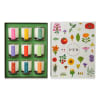 Set of nine scented candles in a gift box beside a floral-illustrated lid