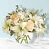 White lilies and peach roses in a clear glass vase