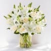 White lilies and cream roses arranged in a clear glass vase.
