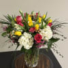 Bouquet of pink and yellow roses with white hydrangeas in a clear glass vase