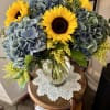 Bouquet of sunflowers and blue hydrangeas in a clear glass vase