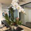 White orchid arrangement in a glass vase with pink protea blooms
