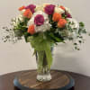 Bouquet of orange and magenta roses in a clear glass vase