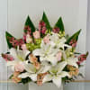 White lilies and pale roses arranged in a box with pink accents