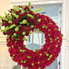 A large funeral wreath built from richly packed red roses creates an