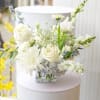 White floral arrangement in a clear square vase with blue accents
