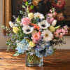 Mixed bouquet in a clear square vase with roses, daisies, and hydrangeas