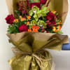 Bouquet of red roses and green orchids wrapped in gold paper