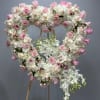 Heart-shaped floral wreath with pink and white roses and orchids on an easel
