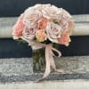 Bouquet of pale pink and peach roses in a clear glass vase with a ribbon