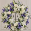 White and purple floral wreath with roses, lilies, and irises on a stand