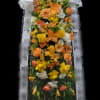 Tall standing floral spray with orange and yellow blooms and a large white bow