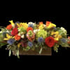 Long floral arrangement in a wooden box with red, yellow, and orange blooms