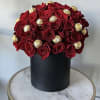Red roses arranged with gold-wrapped chocolates in a black box