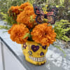 Orange marigold bouquet in a yellow skull vase with a butterfly pick